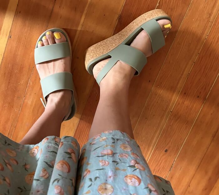 A person wearing light green sandals and a floral dress, stylish and comfortable outdoor essentials for summer.