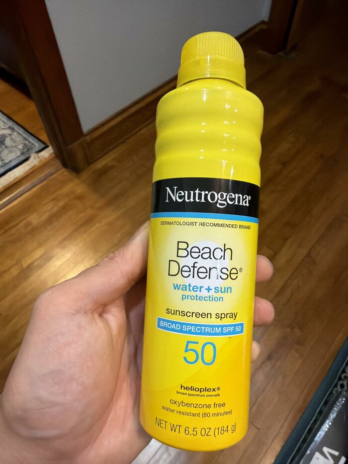 Prime Day outdoor and backyard essentials for summer, a hand holding a yellow bottle of Neutrogena Beach Defense sunscreen spray.