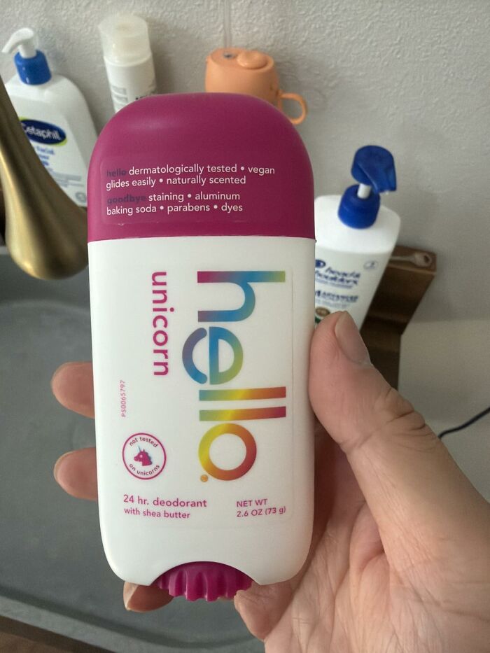 A hand holding a white and pink Hello Unicorn deodorant stick with rainbow lettering. Find Prime Day Deals on beauty products.