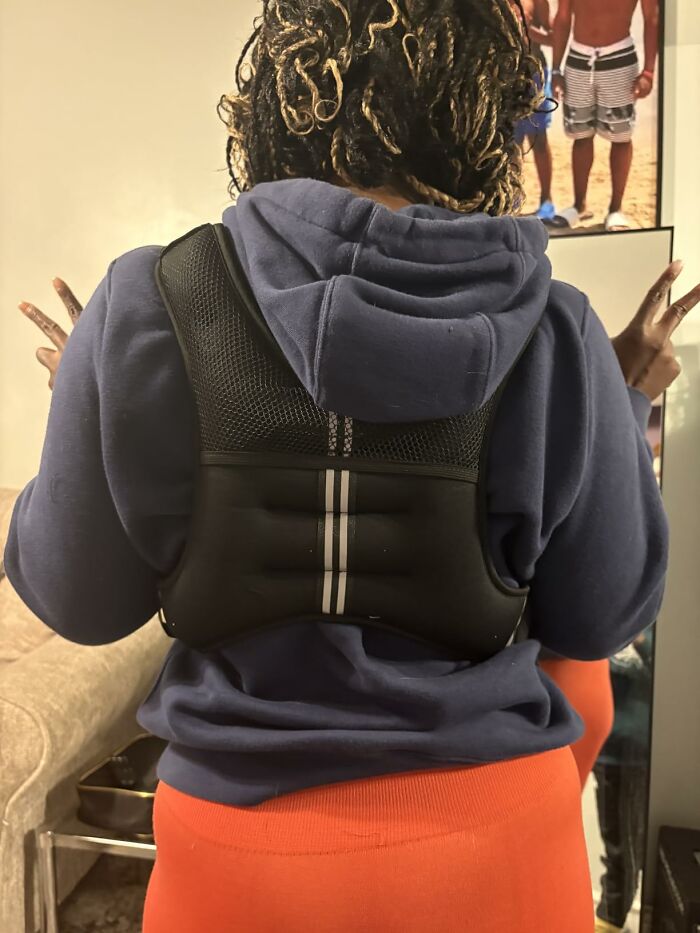 A person from behind wearing a black weighted vest over a blue hoodie and orange leggings, showing fitness gear for Prime Day Deals.