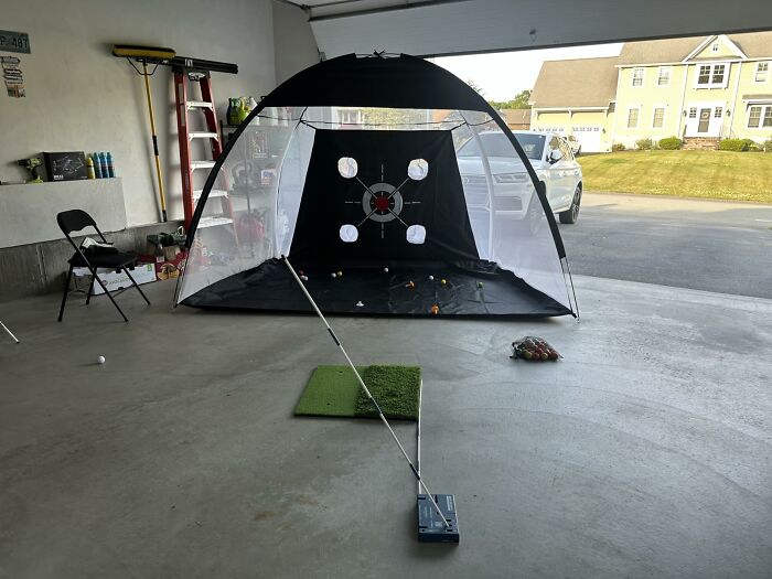 Indoor golf practice net with hitting mat and golf club in garage setup