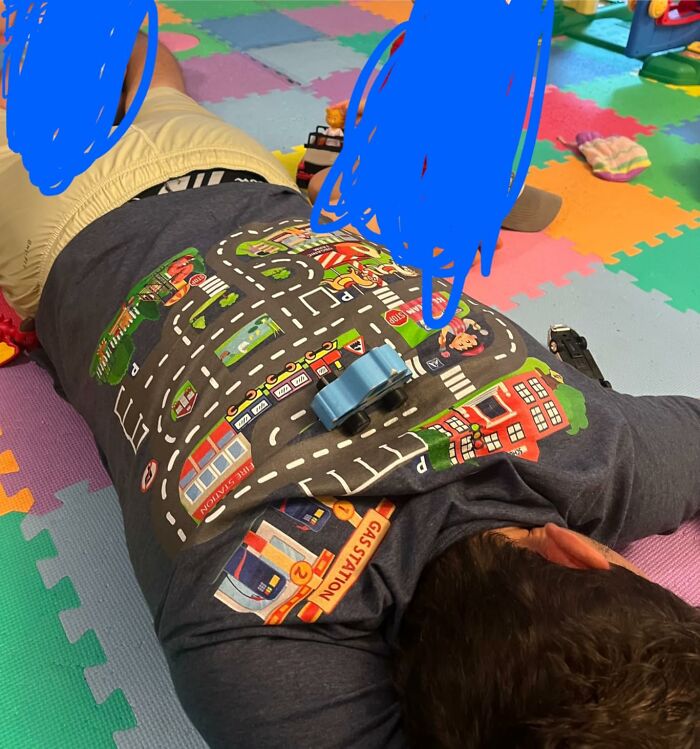 Man lying on colorful playmat wearing road map t-shirt