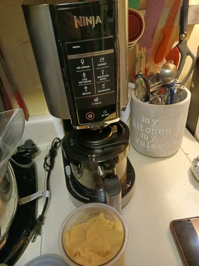A Ninja Creami machine on a kitchen counter, with a container of prepared sorbet below, highlighting its versatility for Prime Day Deals.