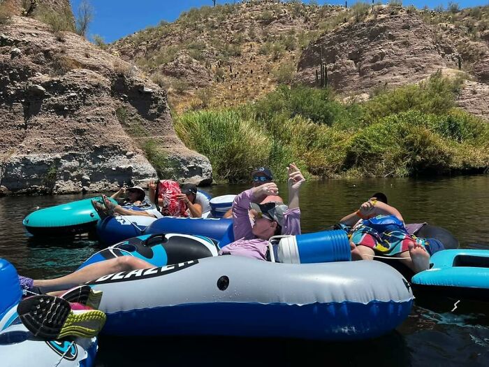Prime Day outdoor essentials: People floating on river tubes, enjoying the summer ease among rock formations and green foliage.