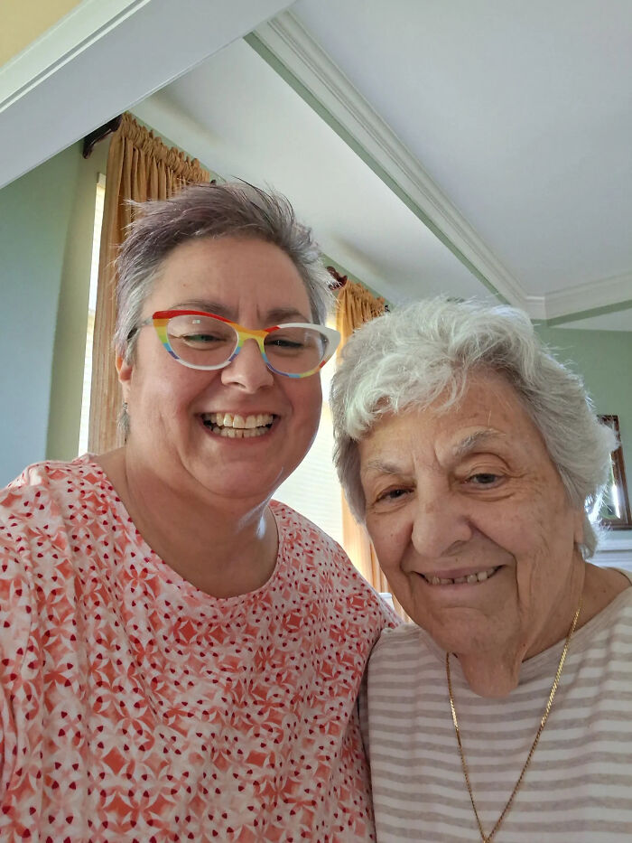 Two happy women, one in colorful glasses, smiling for a selfie, sharing wild coincidences.