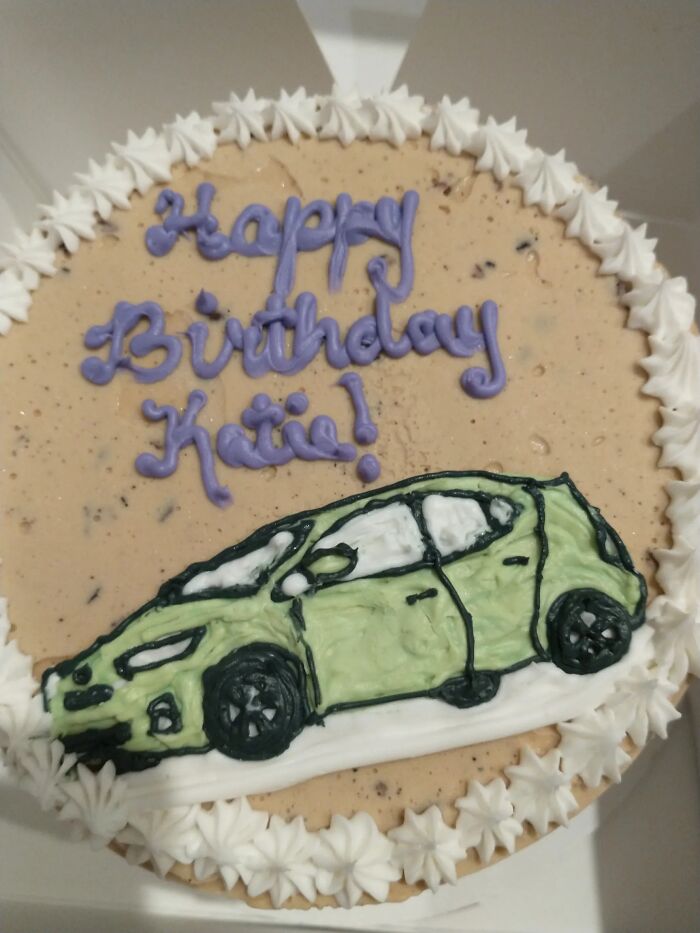 A hilariously messed up cake, a Happy Birthday Katie cake with an unidentifiable green car and a white frosting border.
