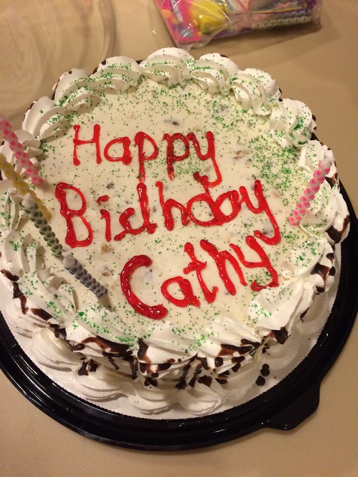 A hilariously messed up birthday cake for Cathy with misspelled Happy Birthday in red icing.