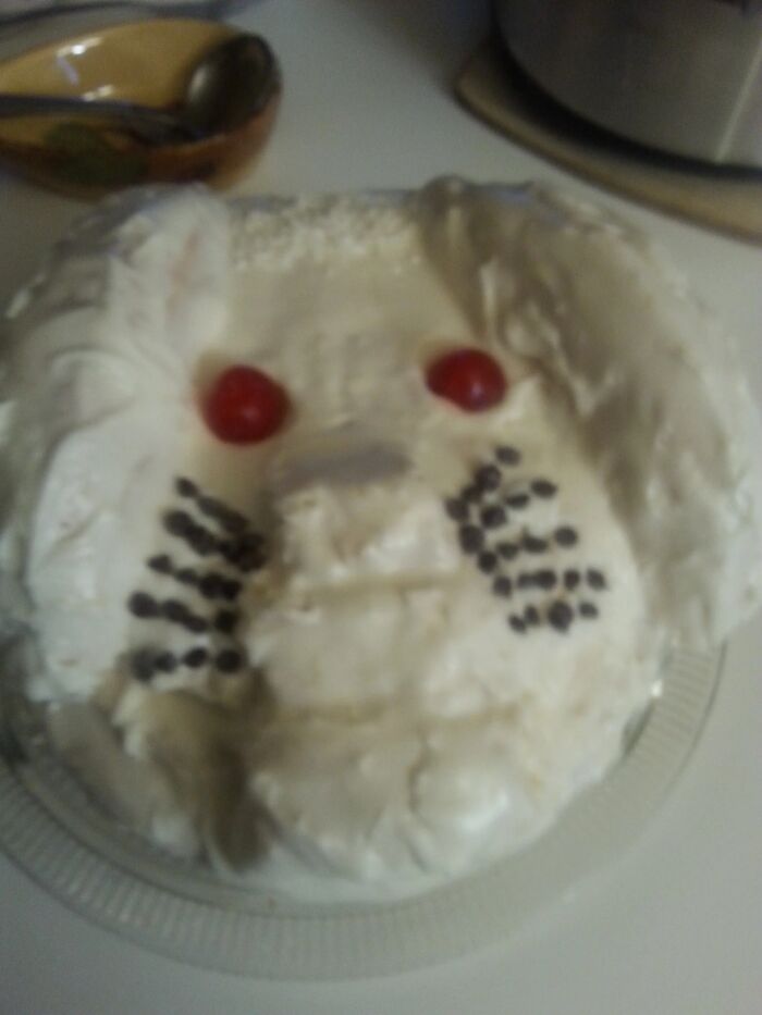 A hilariously messed up cake decorated to look like a face with red cherries for eyes.