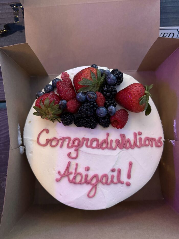 Funny cakes: A white cake with mixed berries on top and a misspelling of 'Congratulations Abigail!' in pink icing.