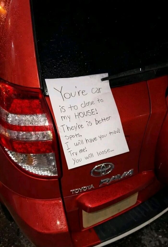 A funny neighbors note on a red car's rear window, warning the driver to move their car.