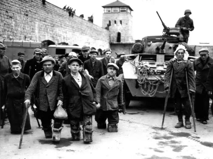 A black and white historical photo shows prisoners and soldiers outside a camp, almost impossible to explain.