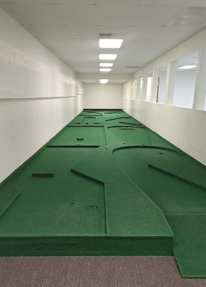 An indoor mini-golf course in a long, empty room creates an unsettling liminal space. The scene descends into the abyss.