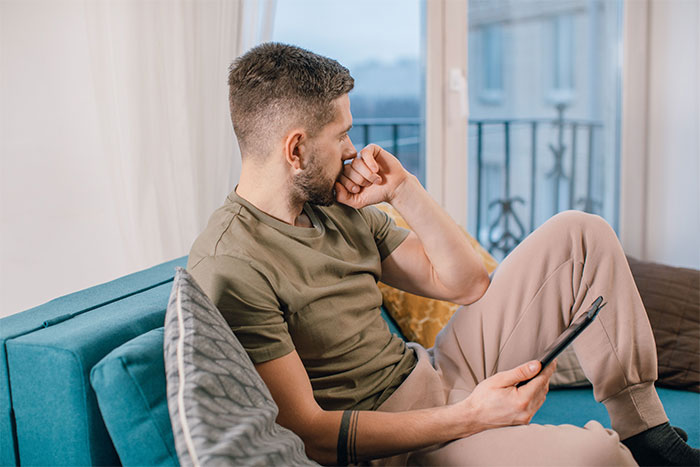 A thoughtful man on a couch, reflecting on how a parent's boyfriend immediately regretted testing a kid's food issue.