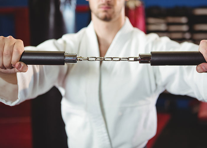 Man in martial arts uniform breaking chain with hands