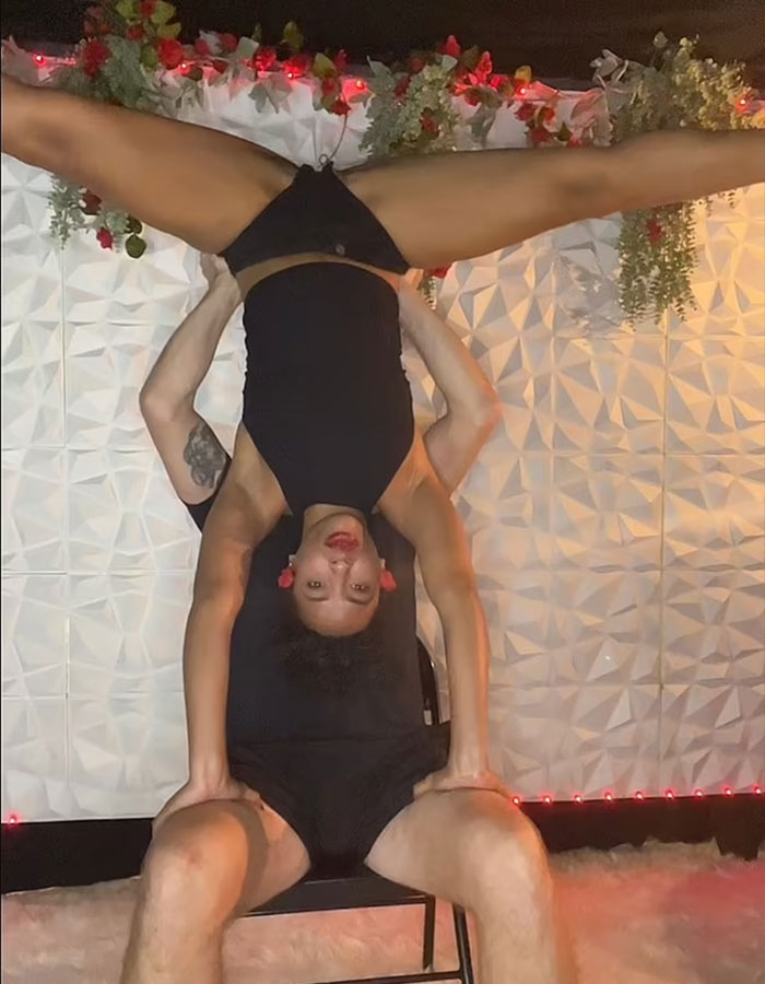 California housewife performs handstand supported by man indoors California housewife performs handstand supported by man indoors