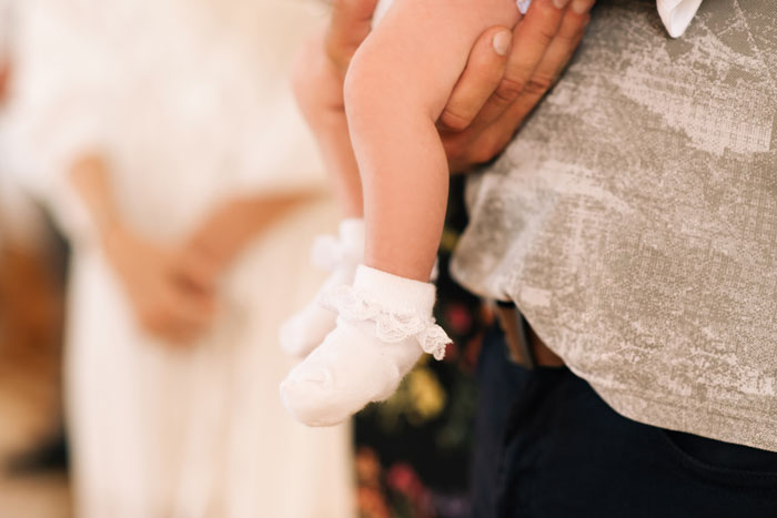 Close-up of baby wearing socks held by an adult at wedding