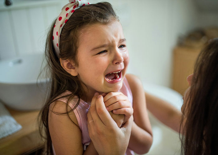 A young girl with a headband crying, holding an adults hands, symbolizing emotional aspects related to autism. A young girl with a headband crying, holding an adults hands, symbolizing emotional aspects related to autism.