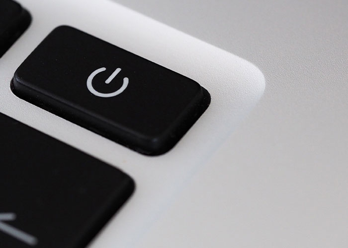 A close-up of a black power button on a silver keyboard, representing a simple solution.