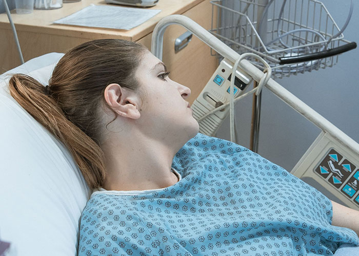 A young woman lying in a hospital bed, looking troubled, symbolizing kids unable to keep contact with their parents.