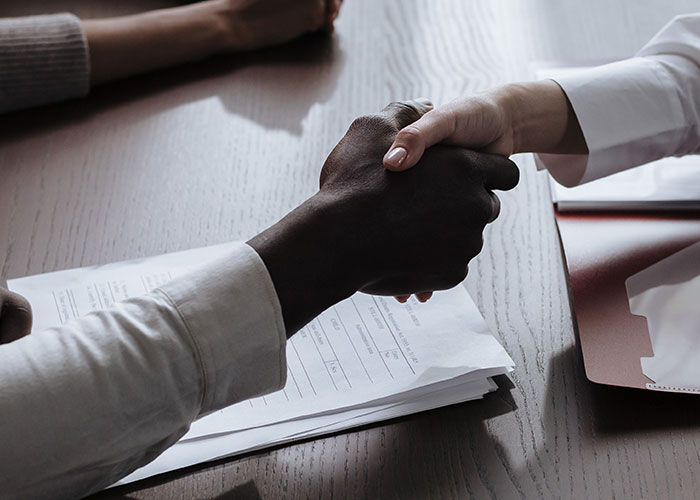 Two people shaking hands over a table, representing advice that is good but socially not acceptable.