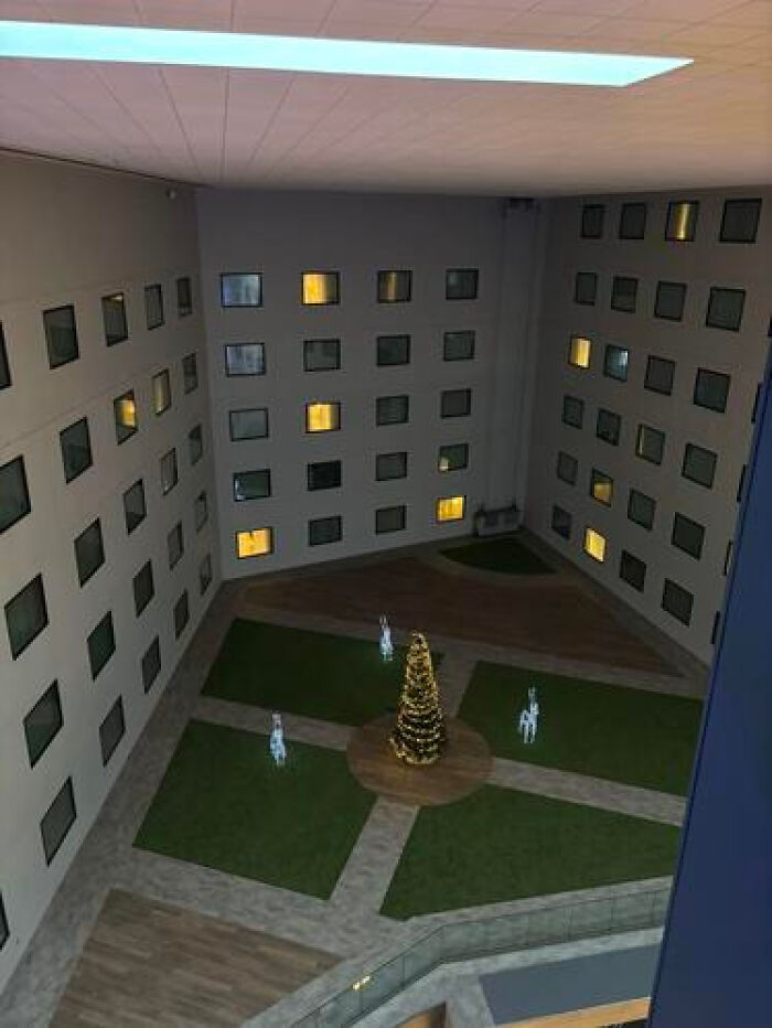 An indoor courtyard with a Christmas tree and small animal figures, showing a haunting liminal space.