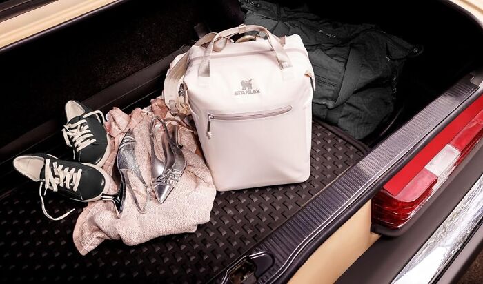 Prime Day outdoor essentials: A white Stanley cooler bag, shoes, and clothes in a car trunk, ready for summer adventures with ease.