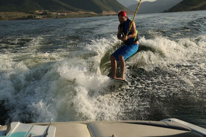 Man wakesurfing behind boat on lake with scenic mountain background Father's Day gifts