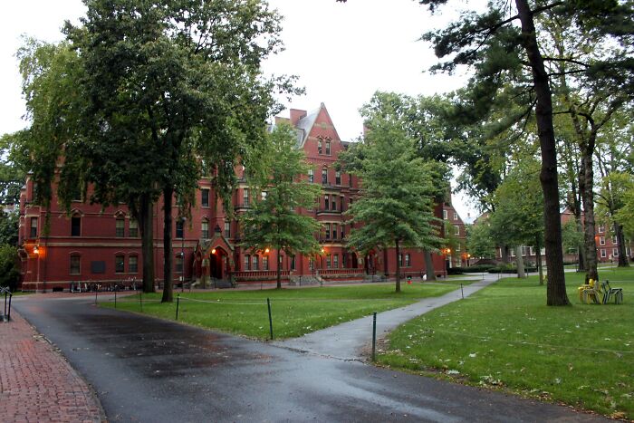 A campus scene with a large red brick building and lush green trees on a cloudy day, highlighting crazy facts.