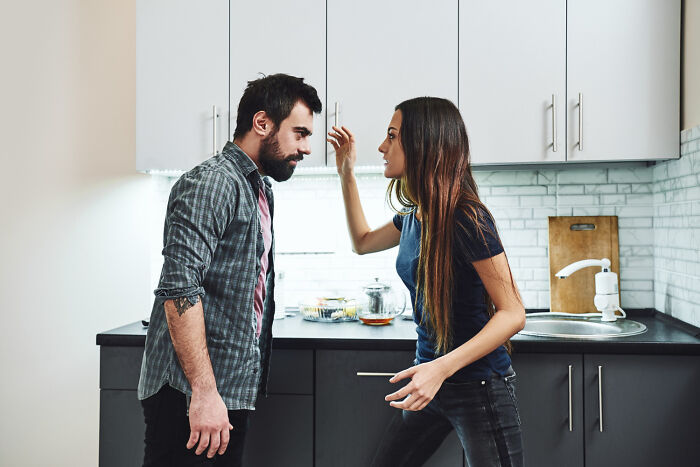 A man and a woman arguing in a kitchen, depicting disturbing things people learn about their friends.