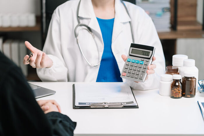 Doctor holding calculator to discuss medical costs