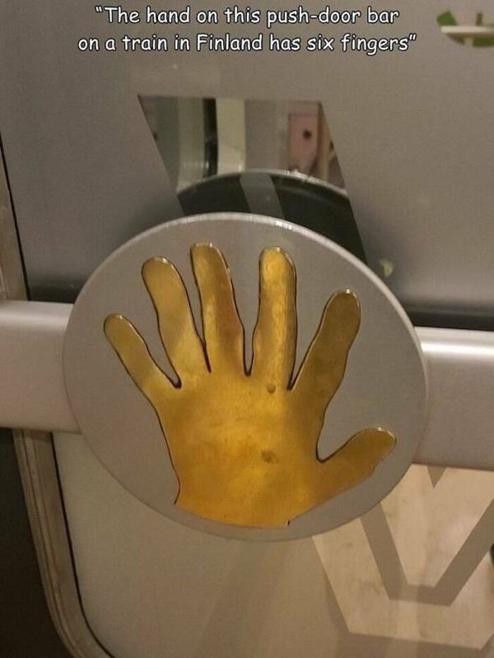 A metal push-door bar on a train in Finland, featuring a golden hand design with six fingers, showcasing a design fail.
