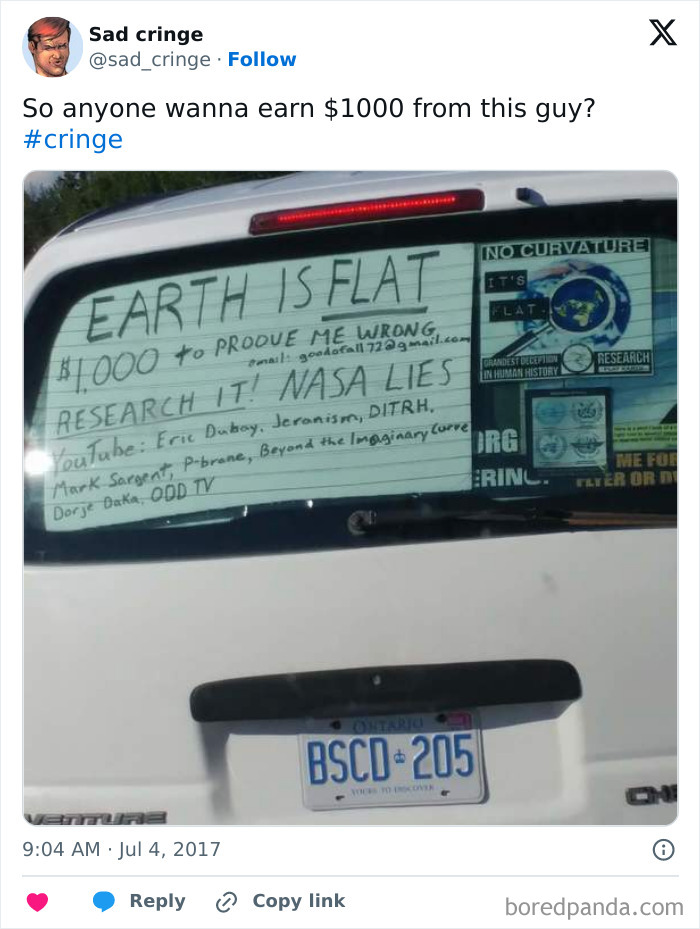 A rear view of a white car with a handwritten sign on the back window claiming Earth is flat, a cringy post.