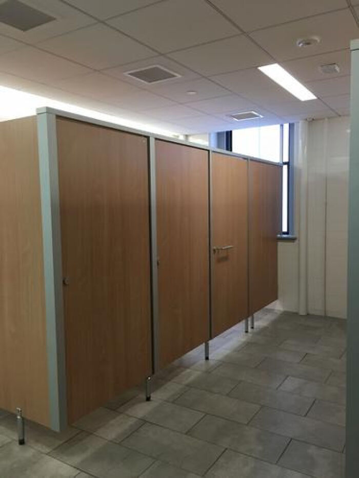 Empty public restroom with rows of stalls, depicting a haunting liminal space.