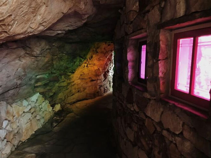 A winding stone pathway inside a cave-like structure with two glowing pink windows, a mysterious liminal space.