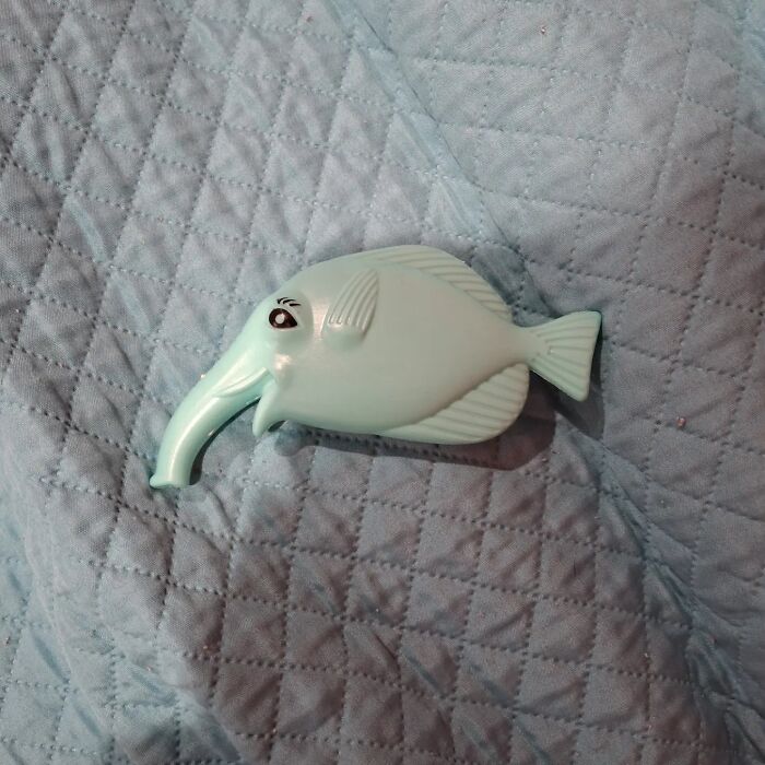A bizarre light blue plastic fish with an elephant-like trunk, a peculiar image.