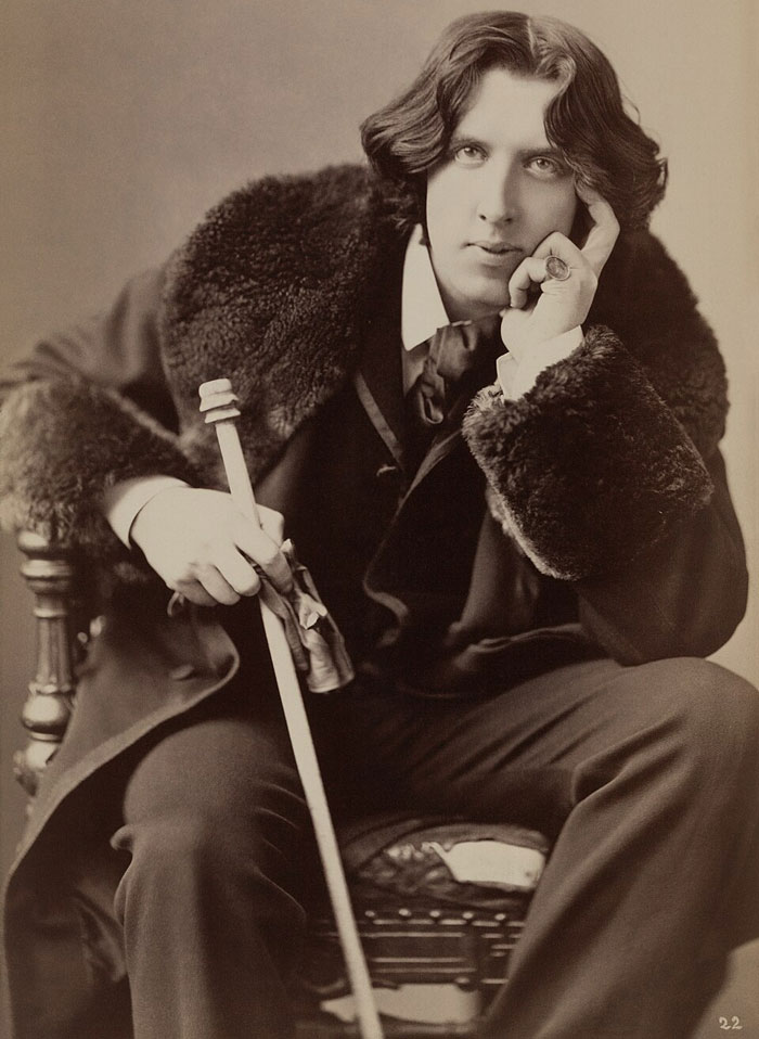Sepia photo of romanticized historical figure in fur coat holding cane