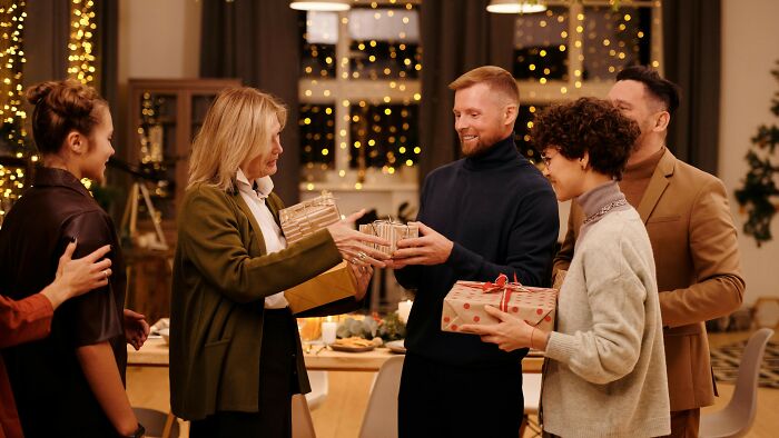 Group exchanging gifts at a holiday party with festive lights in the background