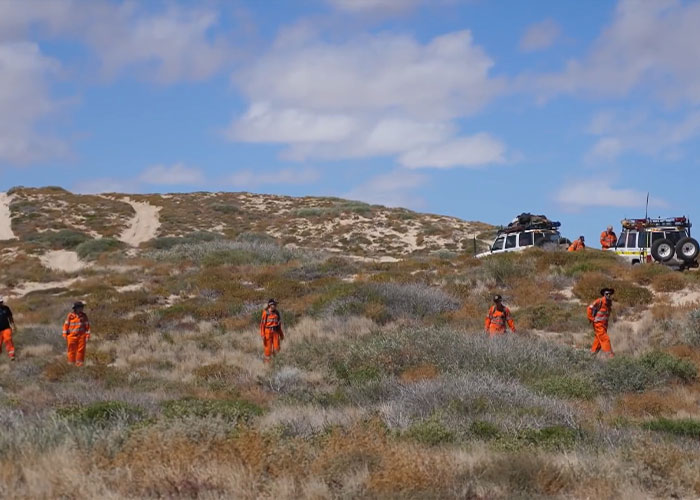 Search team in orange suits exploring campsite area for missing girl Search team in orange suits exploring campsite area for missing girl