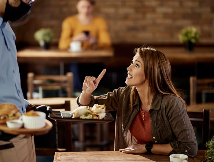 Woman arguing with waiter about food order raised by Karens