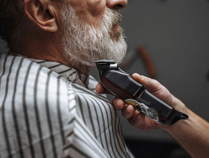 Close-up of a barber trimming an older man's white beard. This image relates to things people saw on their late parents' phones.