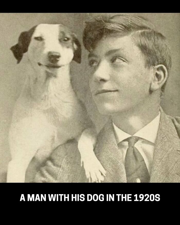 A smiling young man in a suit with his dog perched on his shoulder, a rare and interesting historical photo.