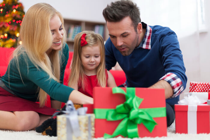 Family opening Christmas presents together with holiday gifts around