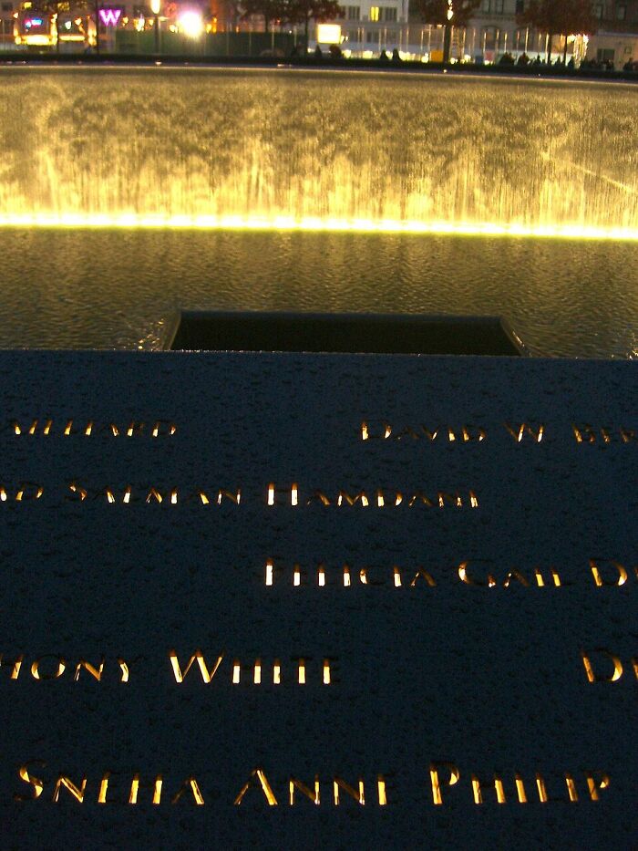 The 9/11 Memorial with names illuminated, symbolizing the unresolved questions in unsolved mysteries.