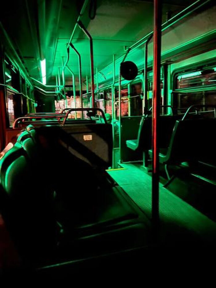 An empty bus interior with an eerie green glow, representing a haunting liminal space.