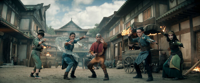 Characters from a major Netflix show in a town square, displaying different martial arts stances amidst casting controversy.