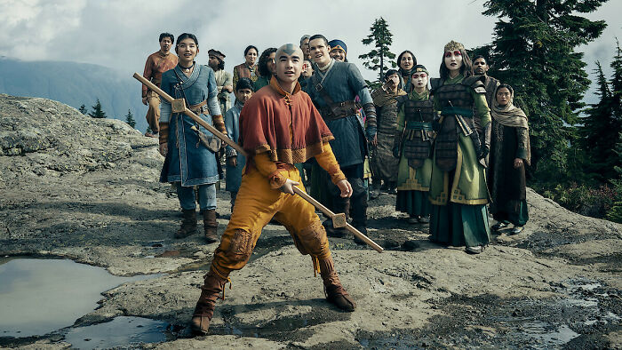 A group of diverse characters from a Netflix show on a rocky mountain, sparking casting controversy.