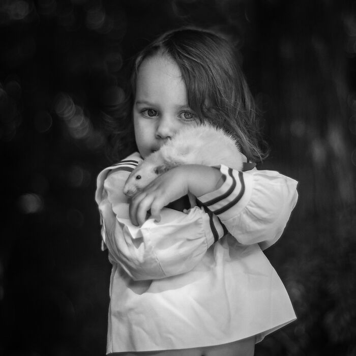 Child holding pet rat close in black and white portrait showing raw beauty of spirit