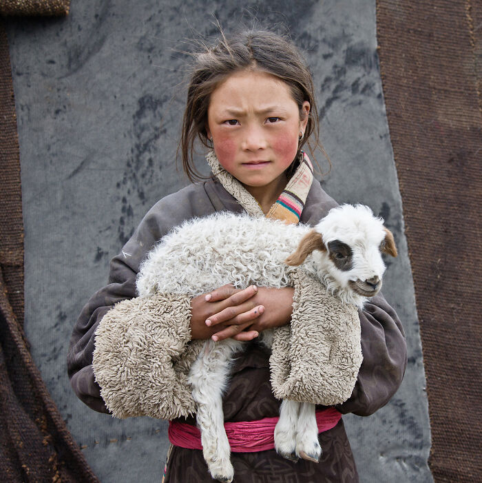 Portrait of a young girl holding a lamb capturing raw beauty of the human spirit
