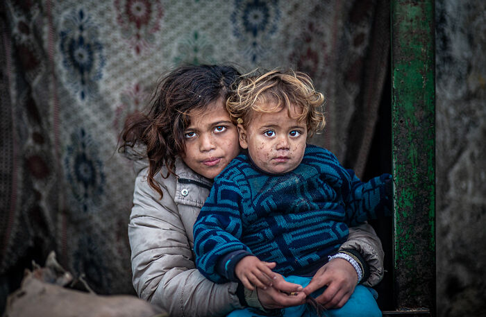 Two children with dirt-smudged faces embodying raw beauty of human spirit