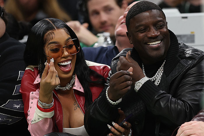 Akon laughs with a woman wearing sunglasses at an event